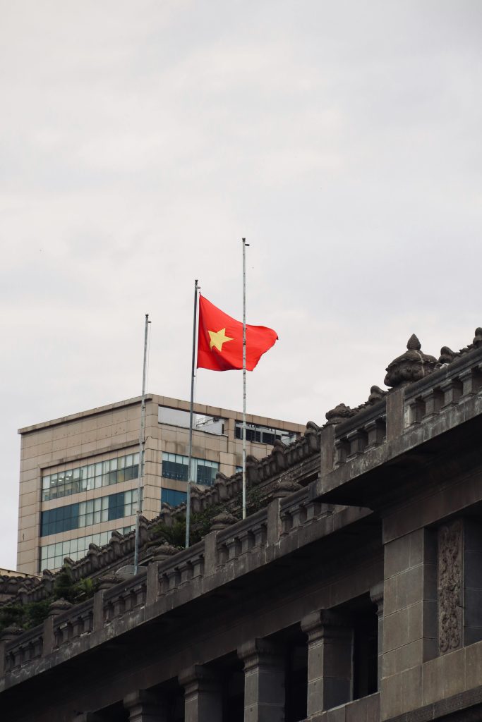 Vietnamese flag flying high on a modern building in a cityscape setting, symbolizing patriotism.