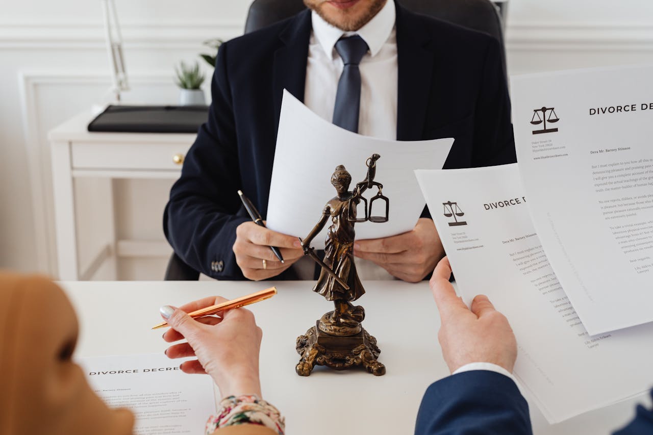 hero-img-01 Legal professionals reviewing divorce documents in a law office with a Lady Justice statue.