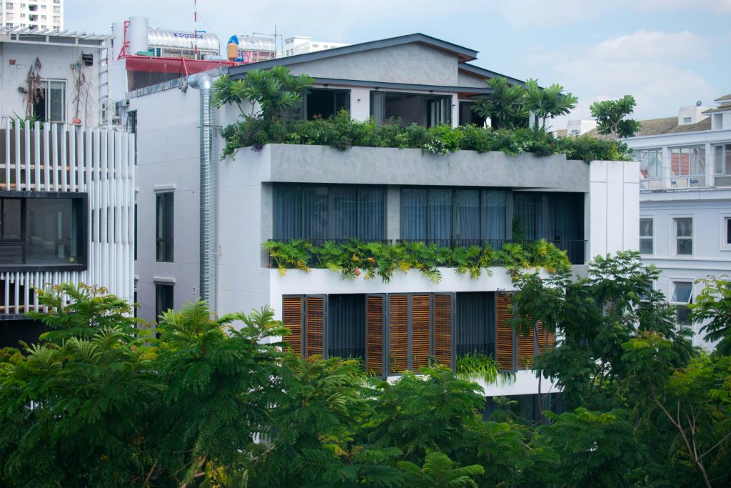 Contemporary urban building with lush green balconies and sleek architecture.